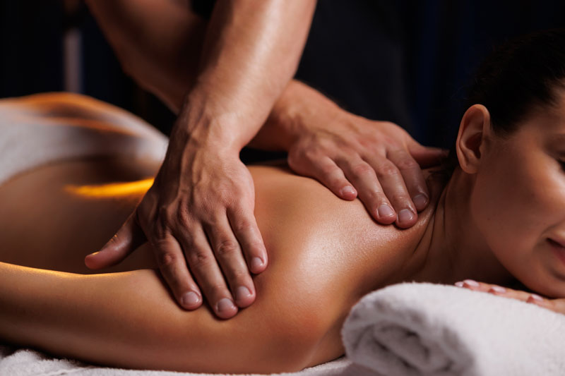 Eine junge brünette Frau erhält in einem Spa-Salon eine professionelle Rückenmassage. Eine wunderschöne nackte Frau in einem Handtuch mit perfekter Haut wird entspannend massiert. Das Konzept der professionellen Luxusmassage